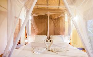 ein weißes Bett mit zwei Schwänen drauf in der Unterkunft Anurak Community Lodge - SHA Plus in Khao Sok