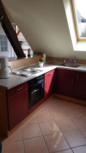 eine Küche mit roten Schränken, einem Herd und einer Spüle in der Unterkunft Urlaubsscheune in Niedergörsdorf