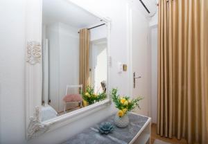 a bathroom with a mirror and a vase of flowers on a table at Apartment & Rooms Meri Tučepi in Tučepi +99 photos