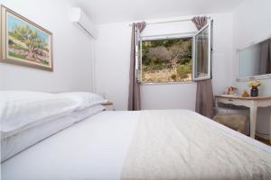 a white bedroom with a bed and a window at Apartment & Rooms Meri Tučepi in Tučepi