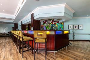 a bar in a room with chairs and a painting on the wall at Cresta President Hotel in Gaborone