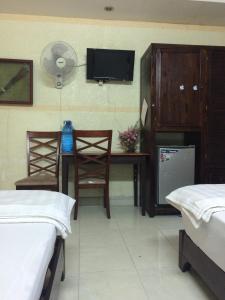 a room with two beds and a table and a tv at Kien Nhi Tam Motel in Vung Tau