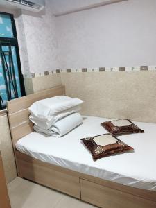 Una cama con sábanas blancas y almohadas. en Hung Fai Guest House en Hong Kong