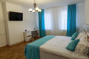 a bedroom with a bed with blue curtains and a television at Strada Mureșenilor - Savas Apartament in Braşov