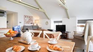 a kitchen and living room with a table with croissants at Saddle and Stable Rooms in Sennen
