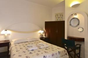 a bedroom with a bed and a desk and a mirror at Chora Resort Hotel & Spa in Chora Folegandros