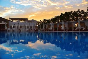a large swimming pool with a sunset in the background at Chora Resort Hotel & Spa in Chora Folegandros