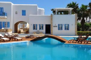 a pool in front of a house with chairs and a bridge at Chora Resort Hotel & Spa in Chora Folegandros