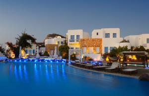 a large pool with chairs and buildings at night at Chora Resort Hotel & Spa in Chora Folegandros