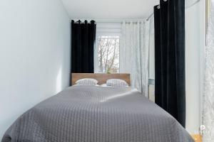 a bedroom with a large bed with black curtains at Jantar Apartamenty - Park Side in Kołobrzeg