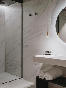 een badkamer met witte marmeren muren en een wastafel bij El Môderne Hotel in Gijón