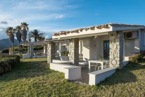 a house with a table and chairs in the grass at Sul Mare Sardegna Villa Anfitrite in Villasimius +7 photos