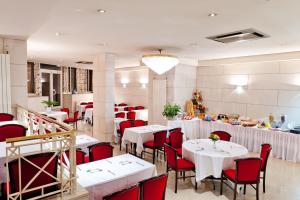 a restaurant with white tables and red chairs at Hôtel Continental in Lourdes
