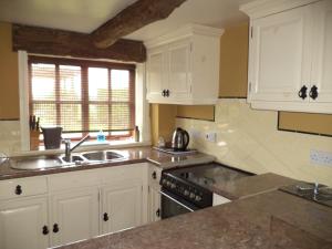 a kitchen with white cabinets and a sink at Moorhen Cottage in Stoke on Trent