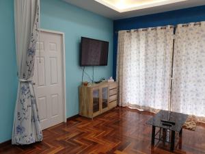a room with blue walls and a television and a wooden floor at Single House Sattahip in Sattahip