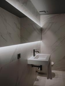 a white sink in a bathroom with marble walls at El Môderne Hotel in Gijón