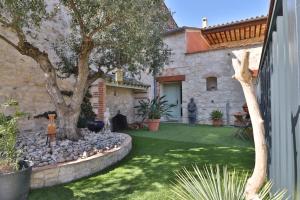 a garden with a tree and a stone house at VILLA ARTEMIA - chambre d hôtes labellisée massages-piscine-climatisation in Sigean