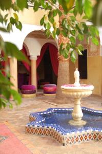 einen Brunnen vor einem Gebäude mit lila Stühlen in der Unterkunft Riad Fatinat Marrakech in Marrakesch