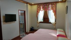 a bedroom with a bed and a window and a television at Casa Familya in Batac