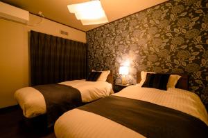 a hotel room with two beds and a wall at villa yawaragi in Fujikawaguchiko
