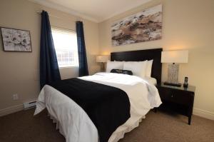 a bedroom with a black and white bed and a window at Premiere Suites - St. John's Signal Hill Gate in St. John's