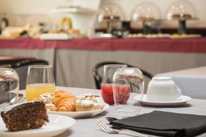 a table with a plate of food and glasses of orange juice at Hotel Montreal in Ragusa