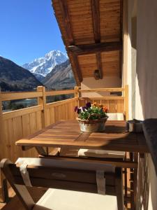 un tavolo in legno con una pentola di fiori sul balcone di La Maison du Pont Mont Blanc 2 a La Salle