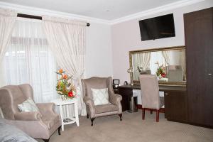 ein Wohnzimmer mit einem Schreibtisch und 2 Stühlen in der Unterkunft Classique Grace Boutique Hotel in Johannesburg