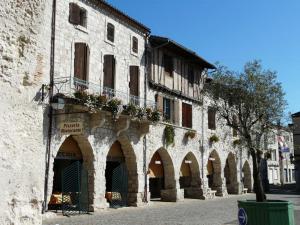 un antiguo edificio con arcos y flores en una calle en Eymet Townhouse, en Eymet