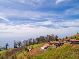 a group of houses on a hill with a blue sky at Rochão Village by Rent2U, Lda in Calheta