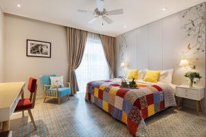 a bedroom with a bed and a desk and a window at Maison De Camille Boutique Hotel in Ho Chi Minh City