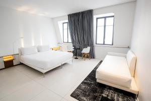 a white bedroom with a bed and a chair at Hotel C2 in Marseille