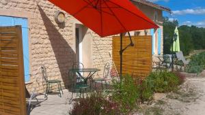 een patio met een tafel en een rode parasol bij LOCATIONS RIVES DE SEUGNE - Claveau in Jonzac