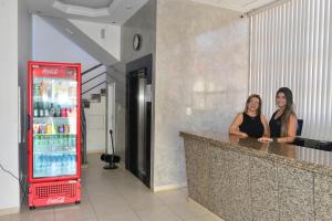 two women sitting at a bar with a soda machine at Del´Fiori Hotel in Ubá