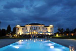 a large building with a pool in front of it at night at Villa Cornaro Tourist Suites in Santo Stefano di Zimella