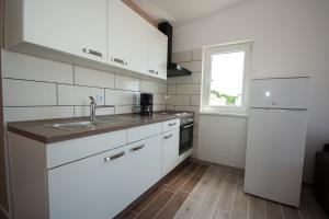 a kitchen with white cabinets and a sink and a window at Apartment Mikuš in Stinica +25 photos