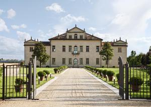 ein großes weißes Haus mit einem Tor und einer Einfahrt in der Unterkunft Villa Cornaro Tourist Suites in Santo Stefano di Zimella
