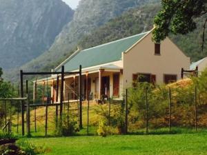 a house with a fence in front of a mountain at Meijer's Rust in De Rust