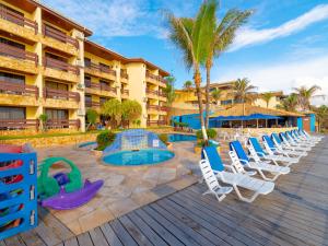 um resort com piscina e espreguiçadeiras e palmeiras em Happy Hotel Praia Azul em Natal