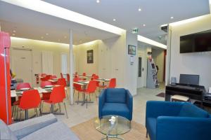 a cafeteria with red chairs and tables and a television at Hôtel du Quai de Seine in Paris