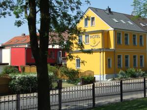 uma casa amarela com uma cerca em frente em Hotel am Weinbergschloss em Waren
