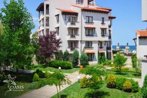 a large white building with a garden in front of it at Oasis Resort Lozenets in Lozenets