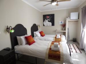 - une chambre avec 2 lits et un ventilateur de plafond dans l'établissement Villa Africa Guesthouse, à Tsumeb