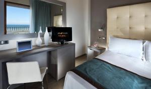 a bedroom with a bed and a desk with a television at Yes Hotel Touring & SPA in Rimini