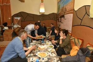 Un gruppo di persone seduti intorno a un tavolo che mangiano cibo di Hotel Baddou a Tamtetoucht