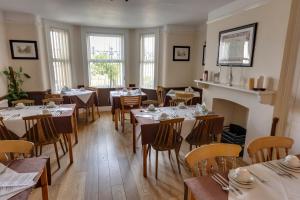 una sala da pranzo con tavoli, sedie e camino di The Sportsview Guest House a Oxford