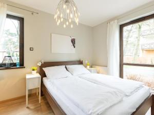 a bedroom with a large white bed with a chandelier at VacationClub – Rezydencja Park II Apartament 1 in Mielno