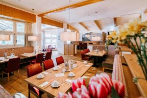 a restaurant with wooden tables and chairs and flowers at Seehaus Riessersee in Garmisch-Partenkirchen