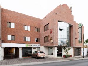 un bâtiment en briques avec une voiture garée devant lui dans l'établissement Hotel Americano, à Arica