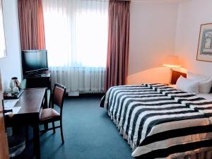 una camera d'albergo con letto, scrivania e TV di Hotel Kölner Hof a Dormagen